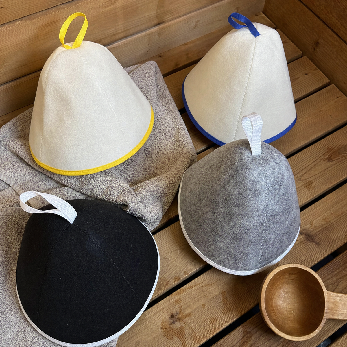 Brand-created UGC-style photo showing four Arctic Nut Banya Hat colorways on a cedar bench