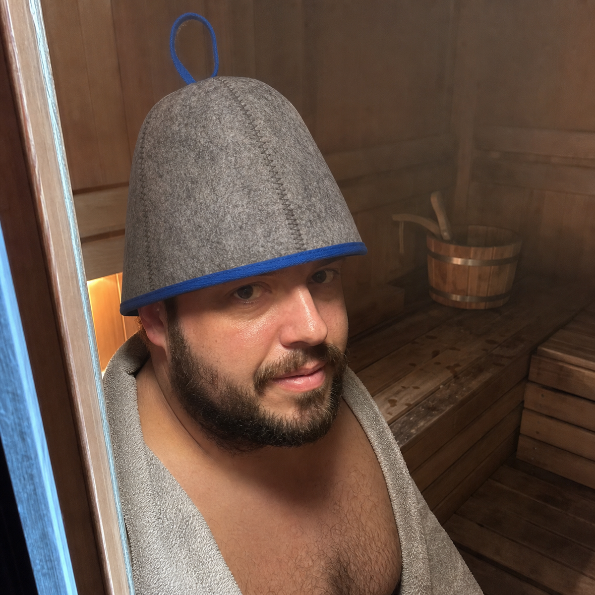 Brand-created UGC-style photo of an adult wearing the gray felt sauna hat with blue trim