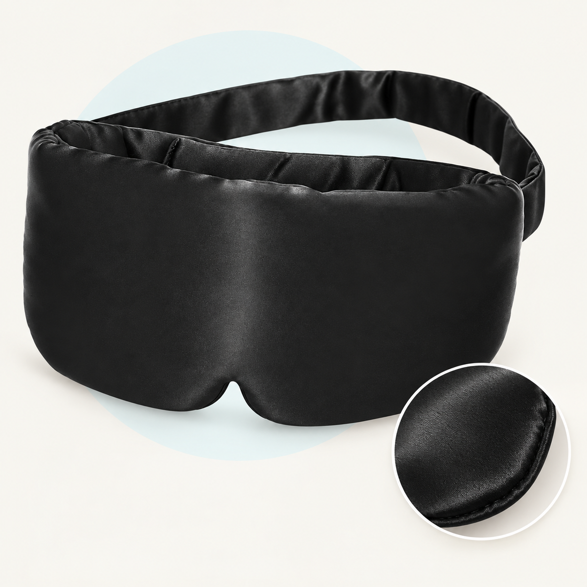 Product study of the black rayon Sleep Mask with broad fabric strap and nose notch, with magnified fabric edge detail