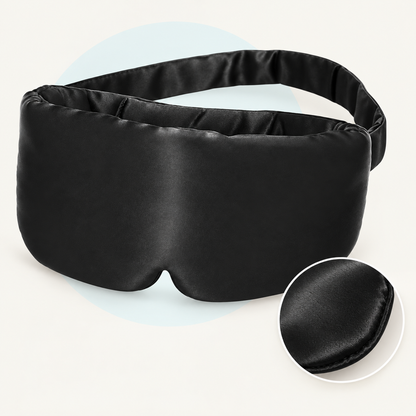 Product study of the black rayon Sleep Mask with broad fabric strap and nose notch, with magnified fabric edge detail