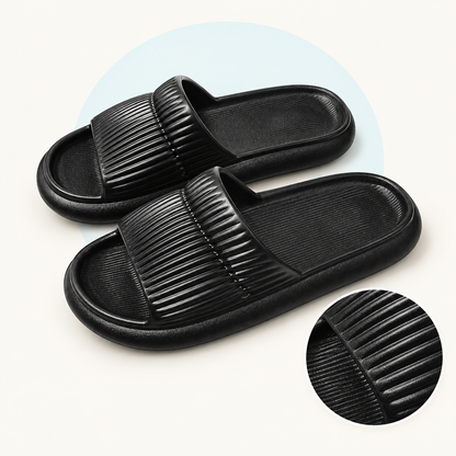 Product study of a pair of black EVA Shower Slides with striped upper bands, with magnified upper and footbed texture