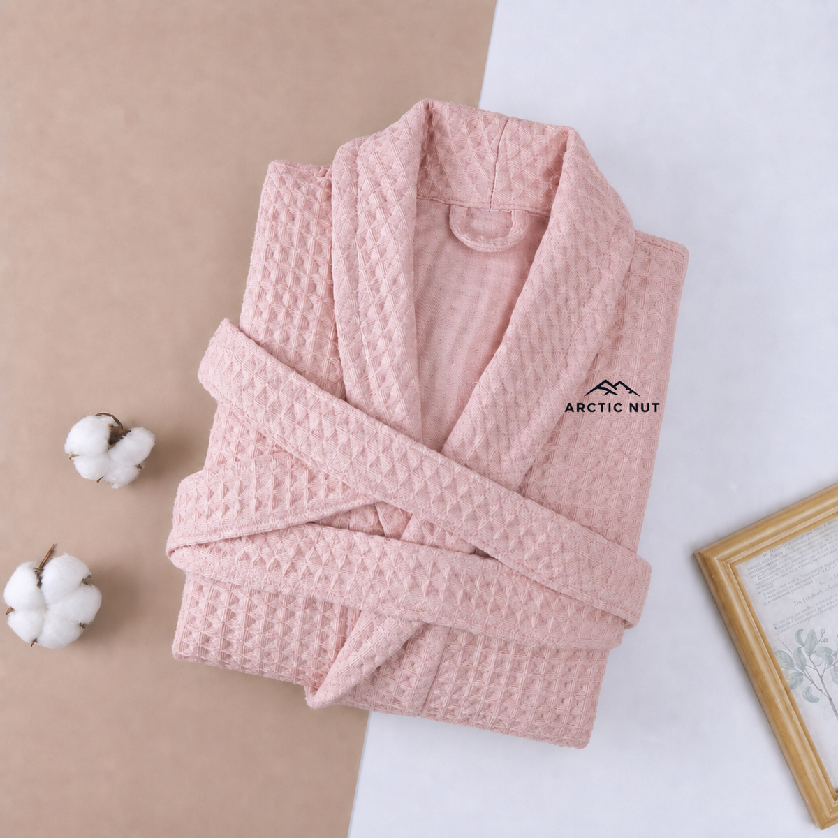 Folded Pink Arctic Nut waffle robe with shawl collar, self belt, and chest logo