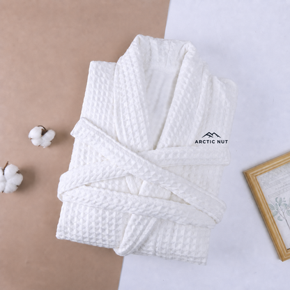 Folded White Arctic Nut waffle robe with shawl collar, self belt, and chest logo