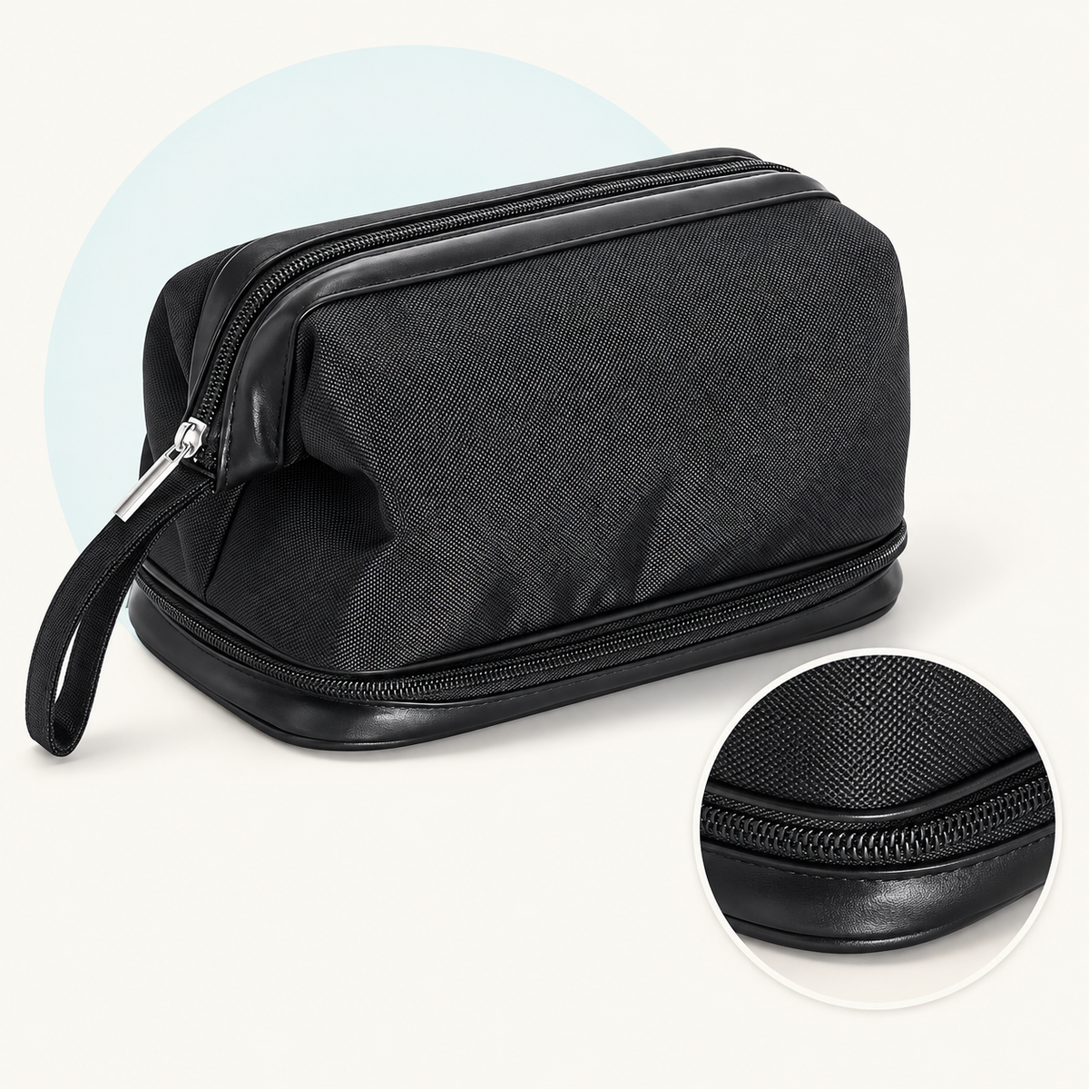 Product study of the black Wash Bag with top zip, wrist strap and separate bottom zip compartment, with magnified lower zipper detail